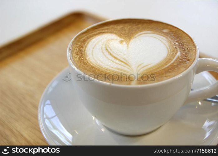 cup of hot latte art coffee on wooden table