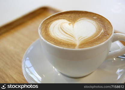 cup of hot latte art coffee on wooden table