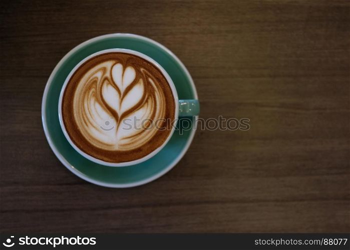 Cup of hot latte art coffee on wooden table