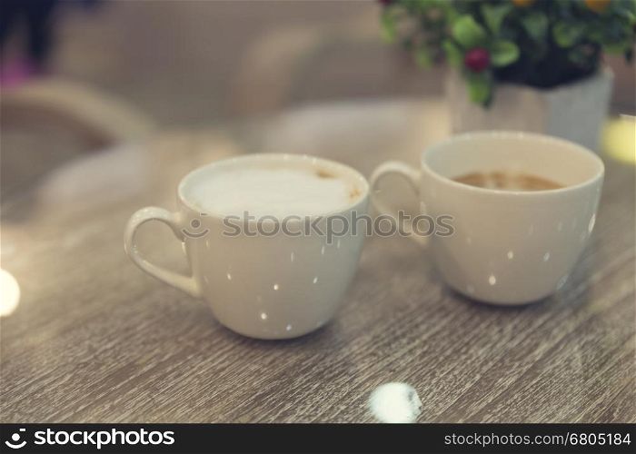 cup of hot latte coffee and bouquet of fake red fruit on wooden table, vintage tone