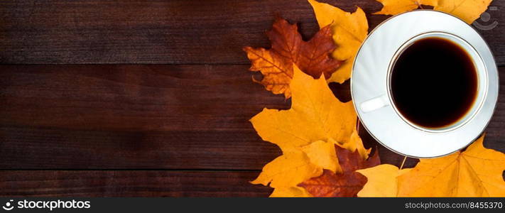 Cup of hot strong coffee and fallen leaves on the wooden background. Hello autumn concept. Warm beverage for cold weather. Copy space. Banner format. Cup of hot strong coffee and fallen leaves on wooden background. Hello autumn concept. Warm beverage for cold weather.
