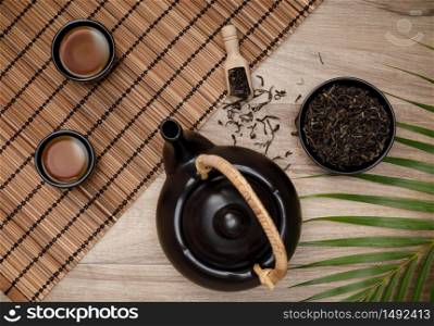 Cup of hot tea with teapot, green tea leaves and dried herbs top view on the wooden table, Organic product from the nature for healthy with traditional style