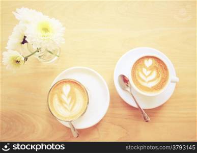 Cup of latte or cappuccino coffee and flower with retro filter effect