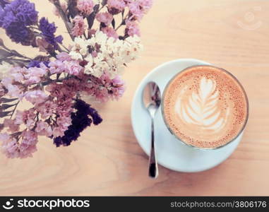 Cup of latte or cappuccino coffee and flowers with retro filter effect