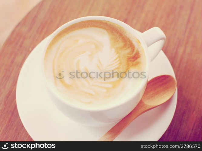 Cup of latte or cappuccino coffee with wooden spoon, retro filter effect