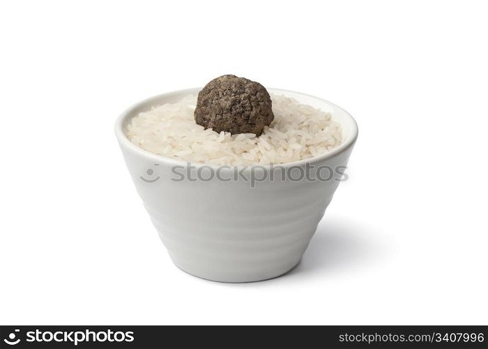 Cup of raw rice with fresh black winter truffle truffle on white background