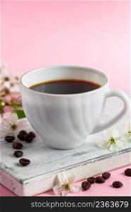 Cup of strong espresso coffee and delicate spring flowers on pink background. Springtime and good morning concept.. Cup of strong espresso coffee and delicate spring flowers on a pink background. Springtime and good morning concept.