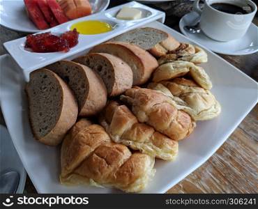 Cup of tasty coffee with tasty breads on wood background