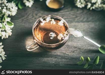 Cup of tea and acacia flowers on rustic wooden background, top view. Healthy seasonal herbal tea