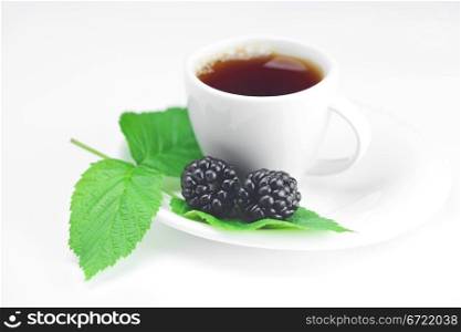 cup of tea and blackberry with leaves on white background