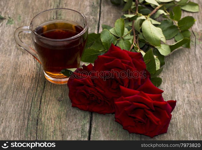 cup of tea and bright red roses on a wooden background, a still life, a subject beautiful flowers and drinks