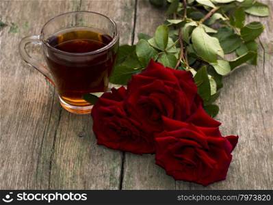 cup of tea and bright red roses on a wooden background, a still life, a subject beautiful flowers and drinks