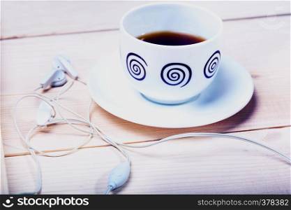 cup of tea and headphones on a wooden surface