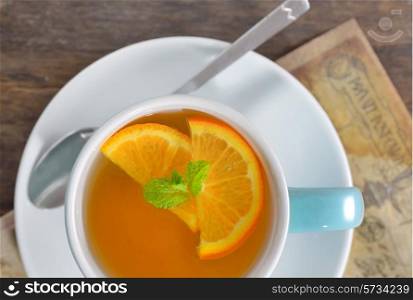 cup of tea and orange slices on old wood table