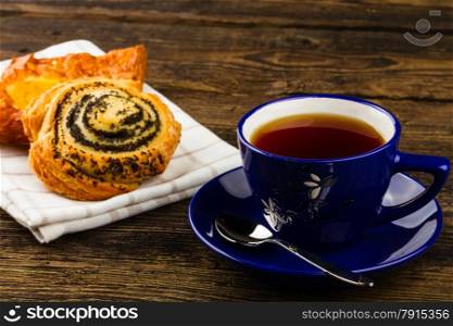 cup of tea and sweet bun on wooden background