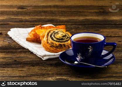cup of tea and sweet bun on wooden background