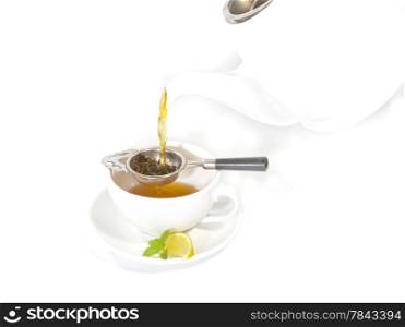 Cup of Tea at High Tea. Pouring tea from a Tea Pot into a white cup with lemon and mint