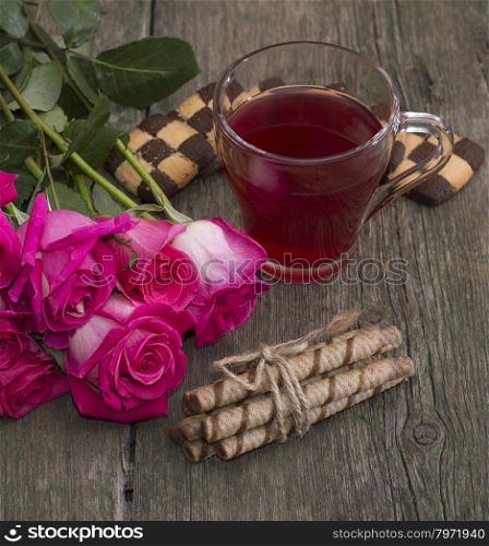 cup of tea, bouquet of roses and various cookies, greeting card on a subject flowers