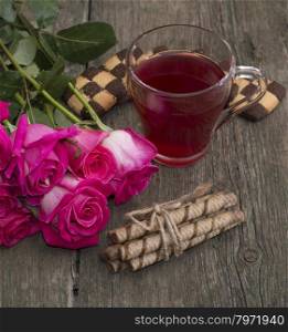 cup of tea, bouquet of roses and various cookies, greeting card on a subject flowers