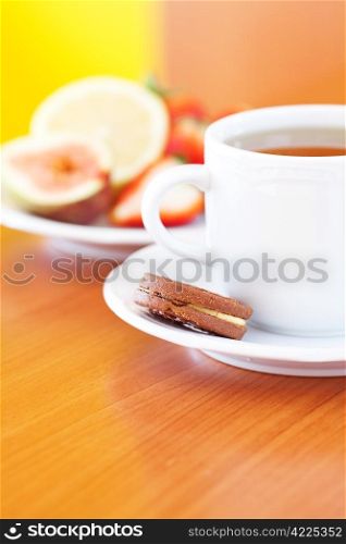 cup of tea,cookie, lemon, fig and strawberries on a plate