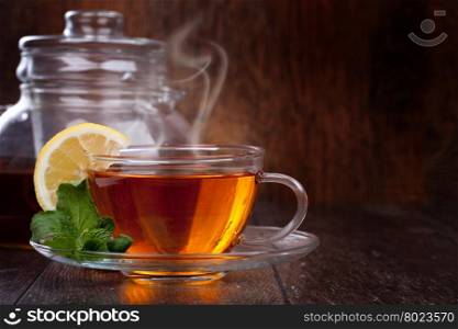 Cup of tea. Cup of tea with mint and lemon on a wooden background
