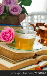 Cup of tea in glass with old books close up. Cup of tea with books