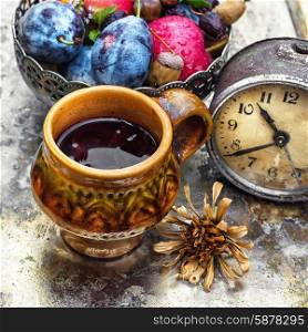 Cup of tea in the autumn style. clay mug with herbal tea on background of apples and plums in the autumn garden