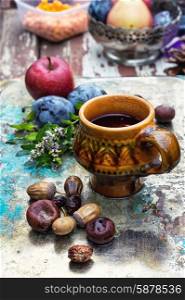 Cup of tea in the autumn style. mug with herbal tea on background of apples and plums in the autumn garden