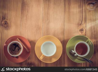 cup of tea, milk, coffee on wooden background