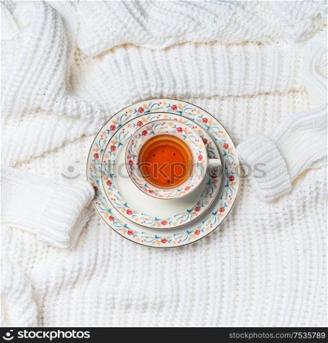 Cup of tea on white knitted sweater, top view. Cold weather season mood. Flat lay . Copy space for your design. Insta style. Modern