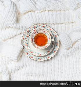Cup of tea on white knitted sweater, top view. Cold weather season mood. Flat lay . Copy space for your design. Insta style. Modern