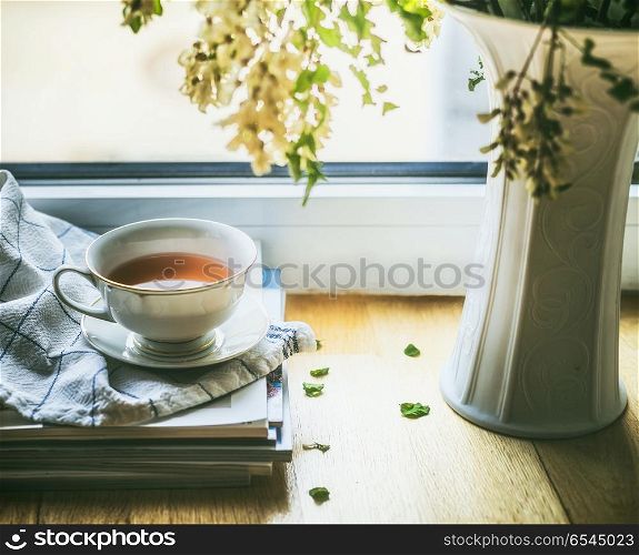 Cup of tea on window still with vase and flowers. Summer still life. Cozy home scene