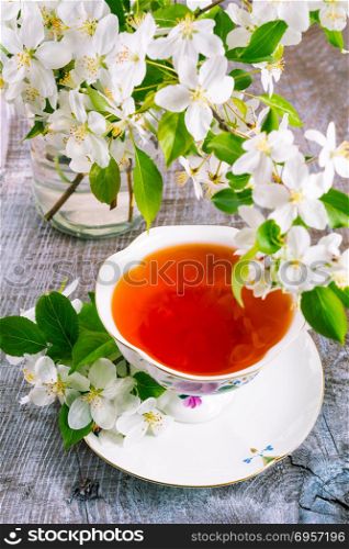 Cup of tea on wooden table and apple blossom. Tea time concept. Breakfast tea cup served with flowers.. Cup of tea on wooden table and apple blossom