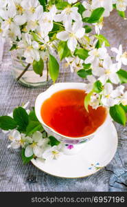 Cup of tea on wooden table and apple blossom. Tea time concept. Breakfast tea cup served with flowers.. Cup of tea on wooden table and apple blossom