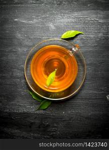 Cup of tea with green leaves. On a black wooden background.. Cup of tea with green leaves.