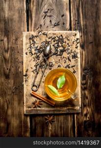 Cup of tea with green leaves. On wooden background.. Cup of tea with green leaves.