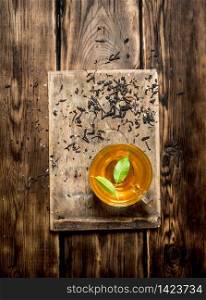 Cup of tea with green leaves. On wooden background.. Cup of tea with green leaves.