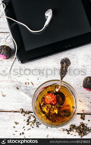 Cup of tea with infused rose and portable computer.Top view. Morning tea and tablet