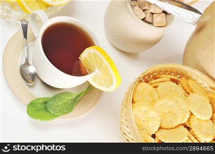 cup of tea with lemon and cookies in basket