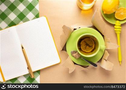 Cup of tea with lemon and honey in torn paper. Mug full of tea