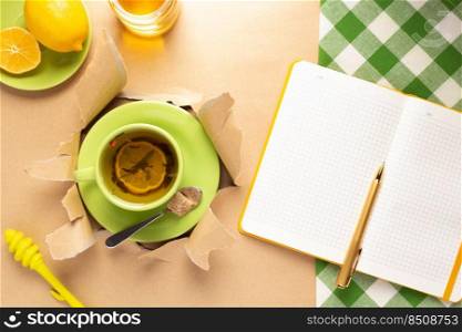 Cup of tea with lemon and honey in torn paper. Mug full of tea