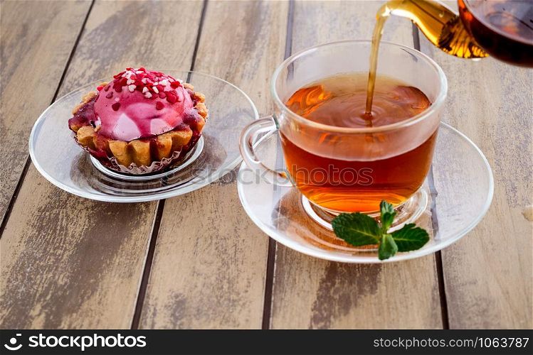 Cup of tea with mint and teapot on a wooden background. cake and cup of tea with mint on a wooden background