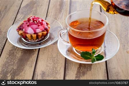 Cup of tea with mint and teapot on a wooden background. cake and cup of tea with mint on a wooden background