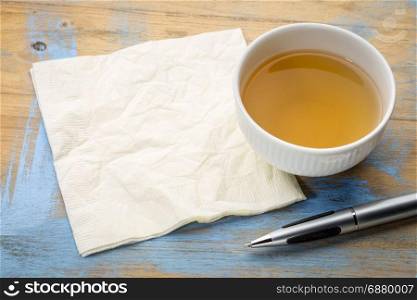cup of tea with napkin and pen on a grunge painted wooden table