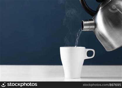 cup of tea with steam. Pouring hot water into into a cup on a dark background. Pouring hot water into into a cup on a dark background. cup of tea with steam. metal kettle