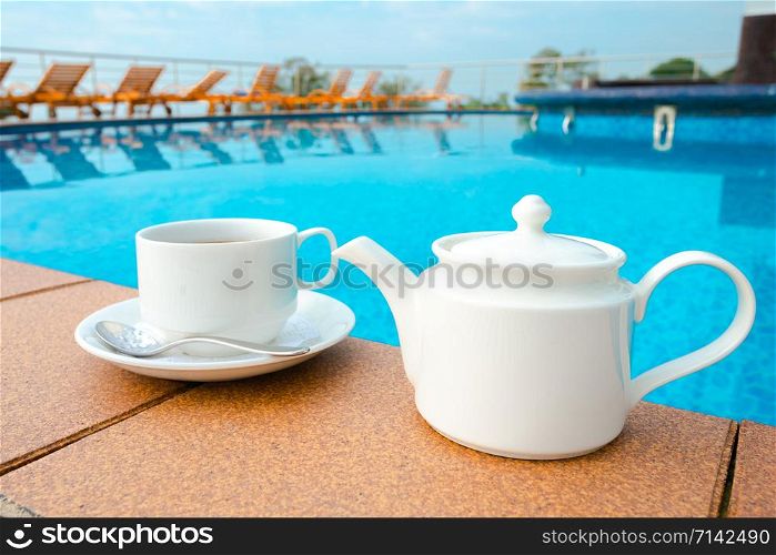 cup on the table near the pool . White ceramic coffee cup