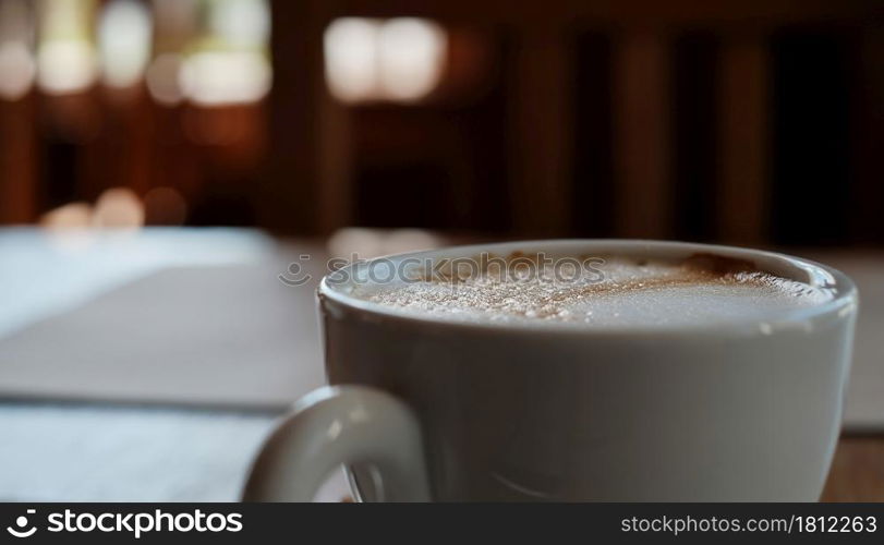 Cup with cappuccino coffee close-up, selective focus on the froth. Coffee break, rest in a cafe with a cup of aromatic latte coffee, an idea for a menu