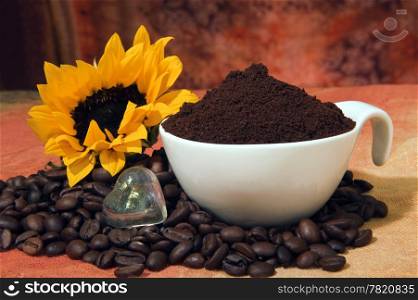 cup with coffee powder and coffee beans scattered on colored background