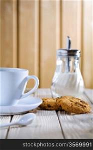 cup with cookies and sugar dispenser on table
