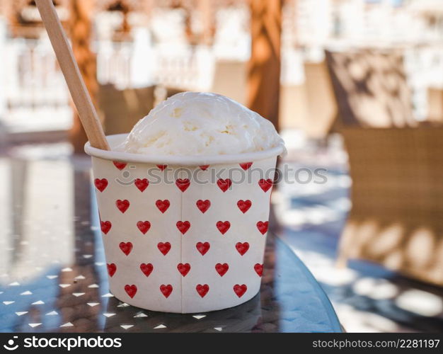 Cup with fragrant ice cream standing on an empty table. Outdoor, close-up. Vacation and travel concept. Cup with fragrant ice cream standing on an empty table